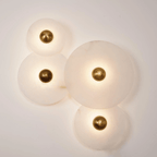 Four-disc alabaster cluster lit on a cream wall, each stone glowing around its brass centre.