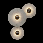 Three-disc alabaster cluster lit against black, each stone glowing around a dark bronze centre.
