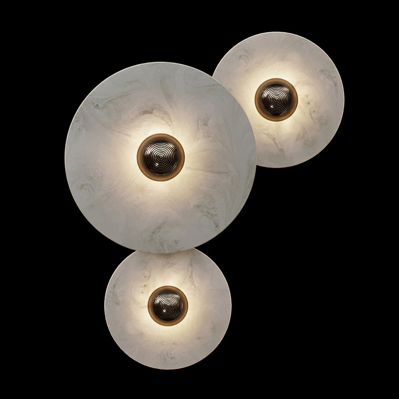 Three-disc cluster on black with light pooling around each bronze boss and fading into the stone.