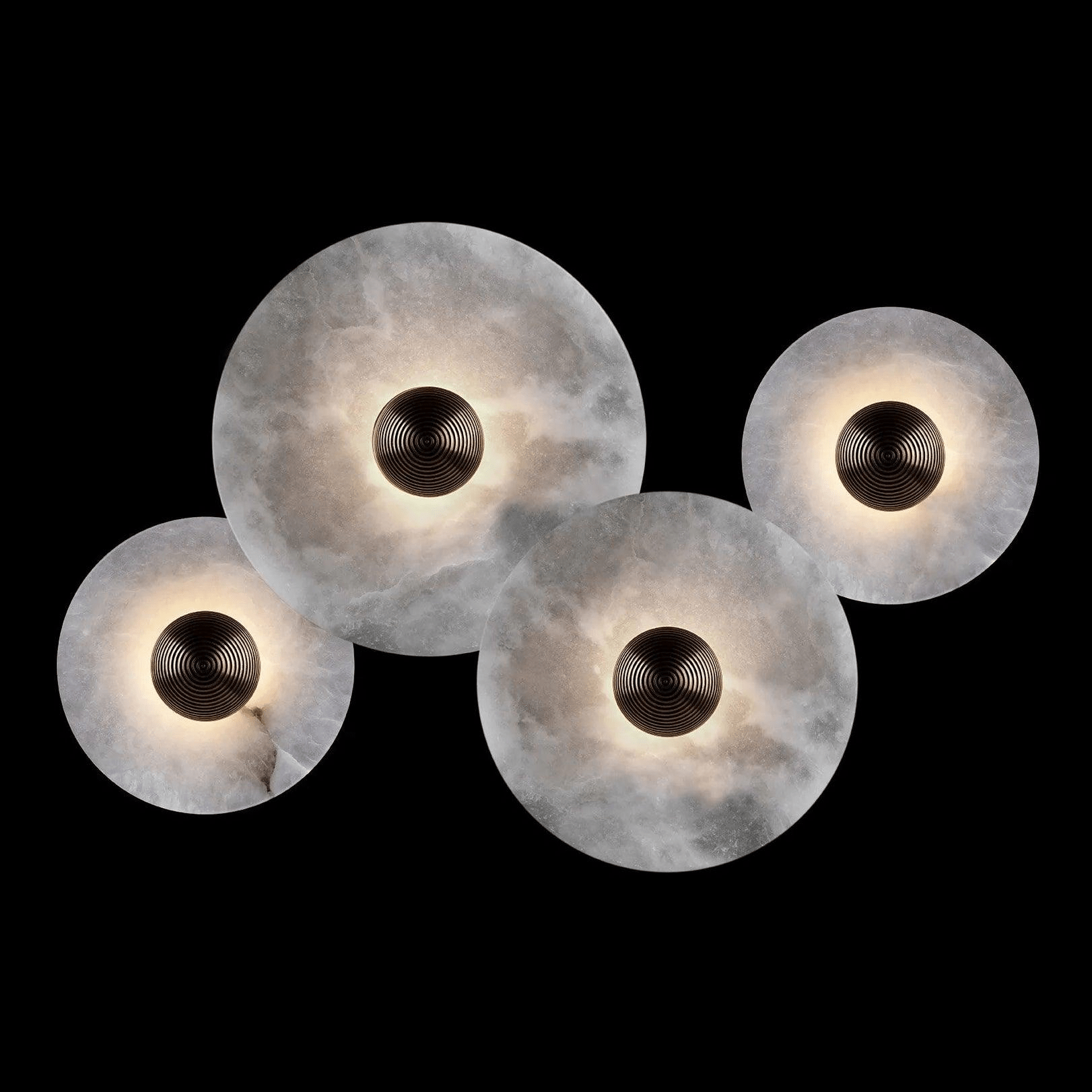 Four lit alabaster discs on black, two large and two small, overlapping in a loose diagonal.