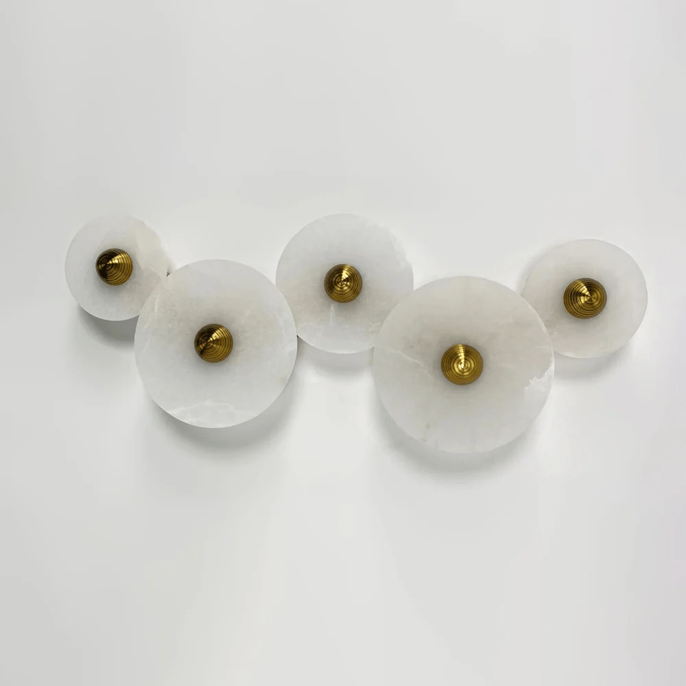 Five unlit alabaster discs in a staggered row, angled to show how far each sits off the wall.
