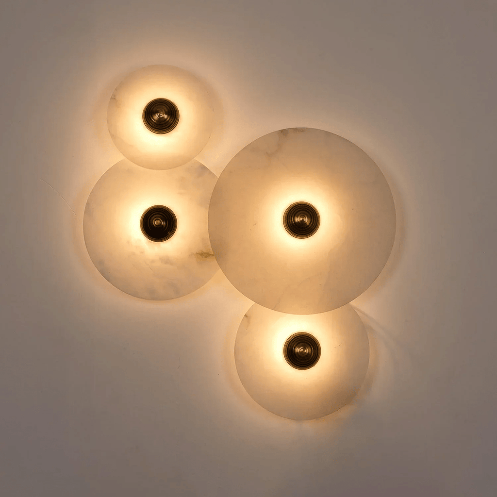 Four-disc cluster lit against a grey wall at dusk, warm pools of light across the stone.