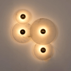 Four-disc cluster lit against a grey wall at dusk, warm pools of light across the stone.