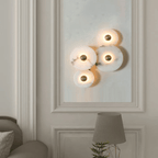 Four-disc alabaster cluster lit on a panelled wall above a table lamp in a classic interior.