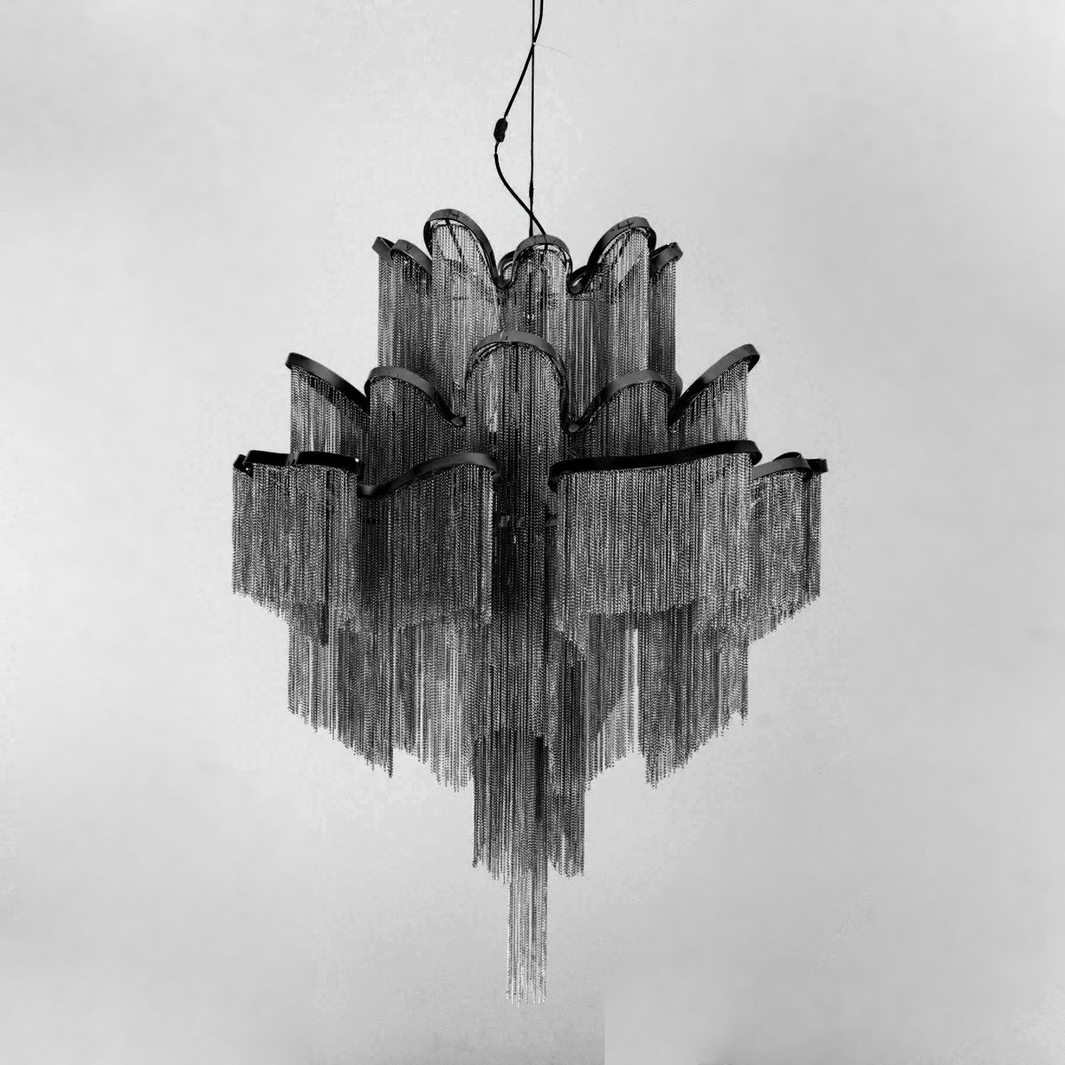 This black Clérachic chandelier is shown unlit against a white backdrop, its tiered silhouette in full view.