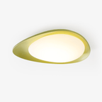 Seen from the side on a light backdrop, the green resin shell of this Clérachic ceiling light glows warm around its diffuser.