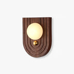 Koyan wall light with an arched, ridged walnut backplate, alabaster globe and small brass knob below.