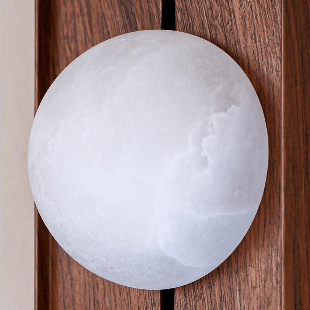 Close-up of the alabaster globe, its cloudy stone veining visible against slatted walnut.