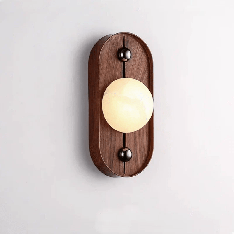 Oval walnut backplate version of the Koyan wall light, alabaster globe held between two dark bronze balls.