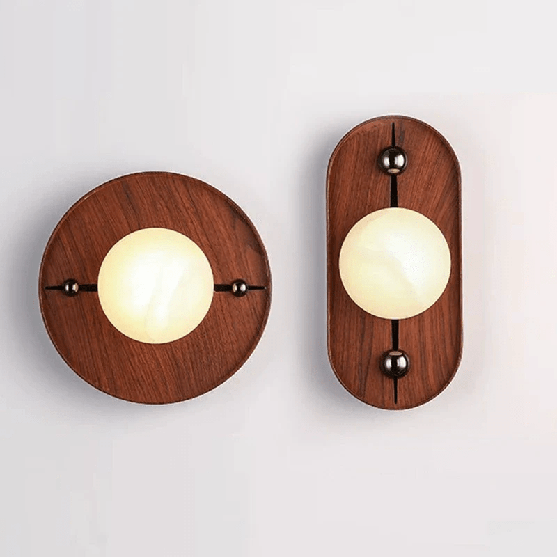 Round and oval Koyan wall lights shown side by side, both lit, for comparing the two backplates.