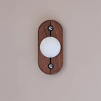 Oval Koyan wall light unlit on a blush wall, straight on, the alabaster globe's veining clearly visible.
