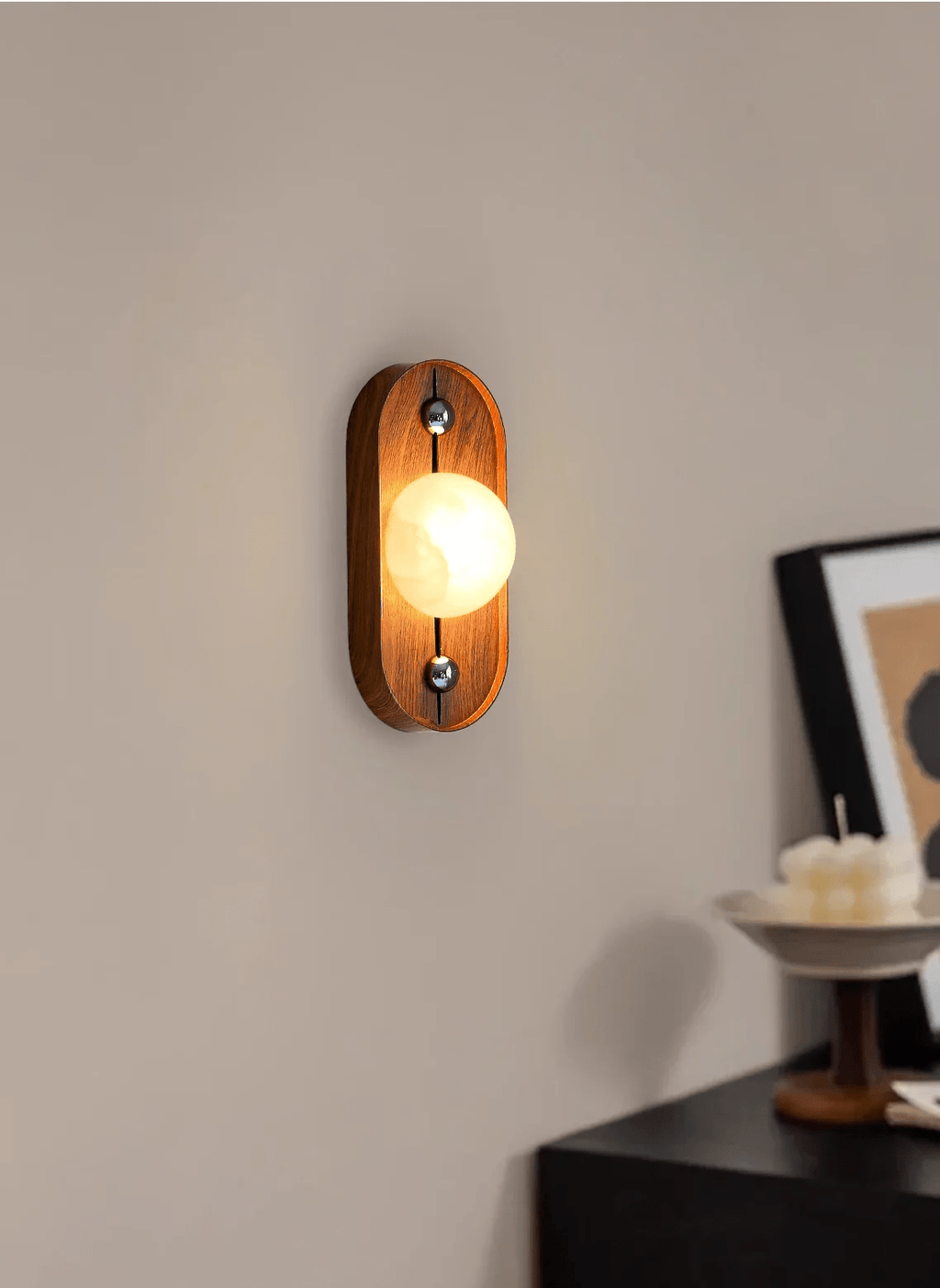 Tall side view of the oval Koyan wall light lit, casting a soft glow across the wall.