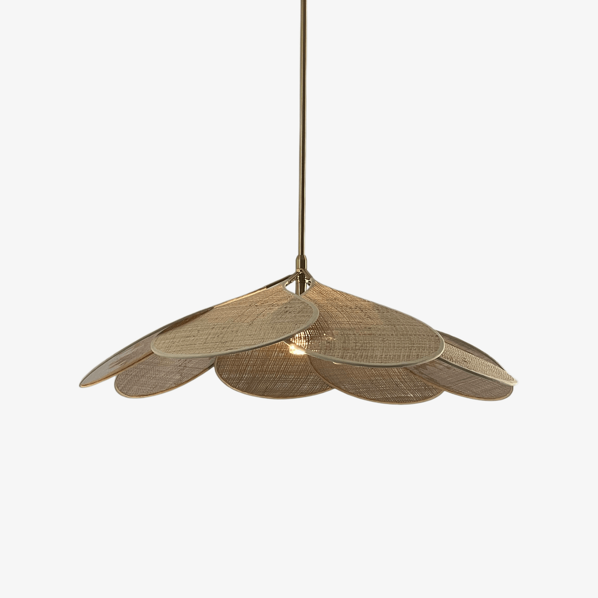 Studio shot of this Clérachic pendant lamp, its natural woven rattan petals fanned into a dome on a brass stem.