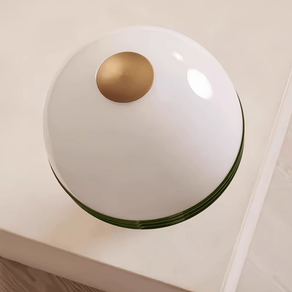 Overhead close-up of the Clérachic table lamp's glass dome, showing the small brass finial at its centre.