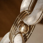 Macro of one joint: a brass sphere and studded brass collar clasping two alabaster links