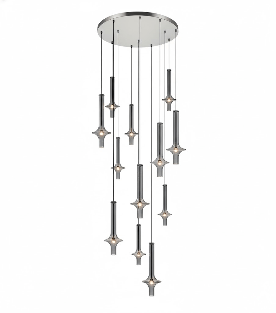 A cascade of Clérachic pendants in dark graphite-toned glass drops from a round canopy in tiers, lit against a white backdrop.