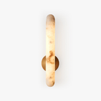 Studio view on white of the lit rod sconce, brass mount visible behind the glowing stone.