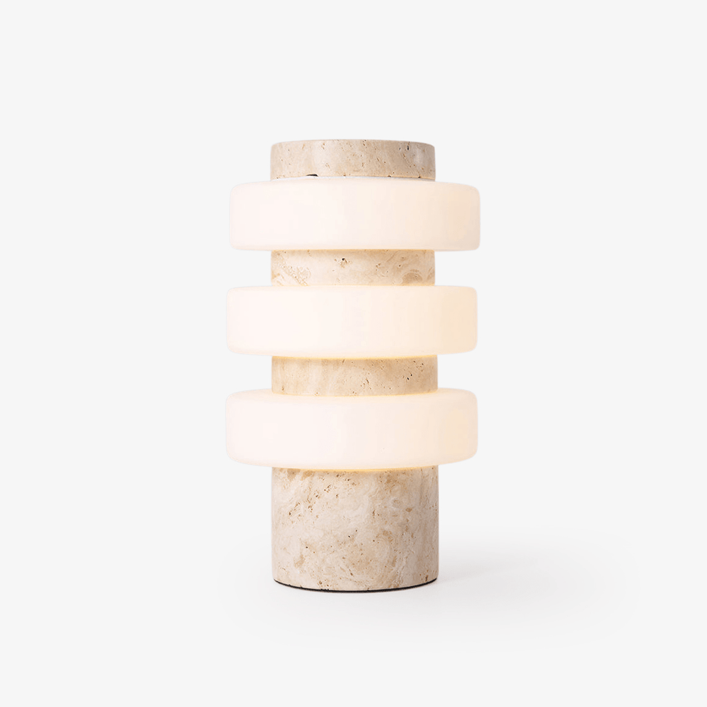 Clérachic stone table lamp with three lit glass rings stacked around a travertine-textured column, photographed alone on a plain white background.