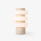 Clérachic stone table lamp with three lit glass rings stacked around a travertine-textured column, photographed alone on a plain white background.