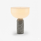 This Clérachic sphere table lamp in grey marble, lit and photographed against a plain light grey background.