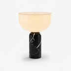 This Clérachic sphere table lamp in black marble, lit and photographed against a plain light grey background.