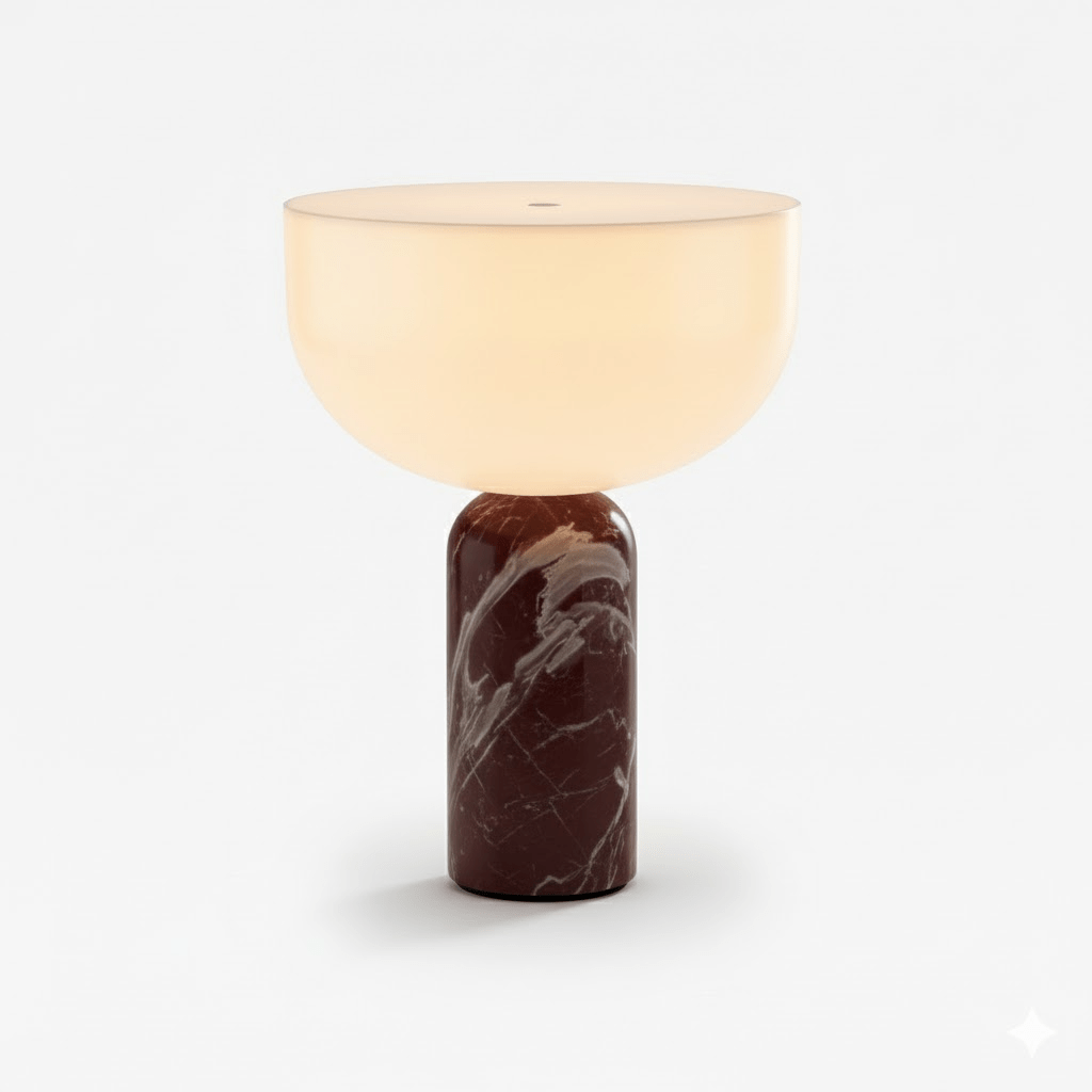 This Clérachic sphere table lamp in dark red marble, lit and photographed against a plain light grey background.