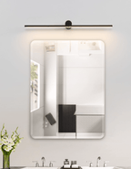 A lit Clérachic wall light spans a rounded rectangular mirror in a white bathroom.