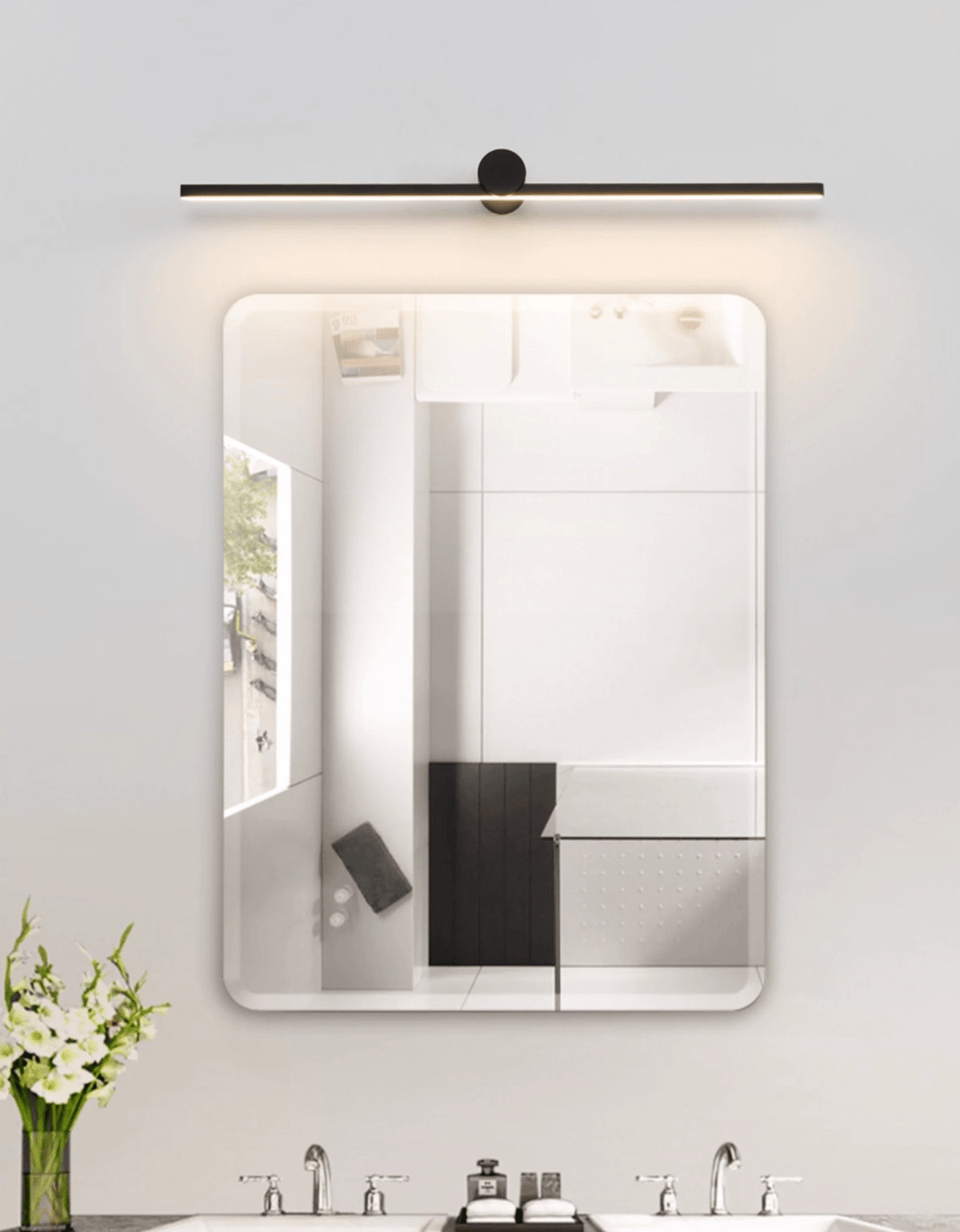 A lit Clérachic wall light spans a rounded rectangular mirror in a white bathroom.