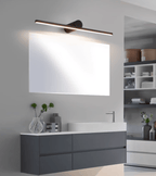 A lit Clérachic wall light spans a wide mirror above a grey bathroom vanity with a vase of greenery.