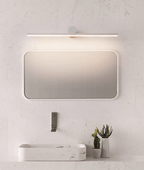 This Clérachic wall light appears in a pale finish here, spanning a rectangular mirror above a marble vanity with a small cactus.