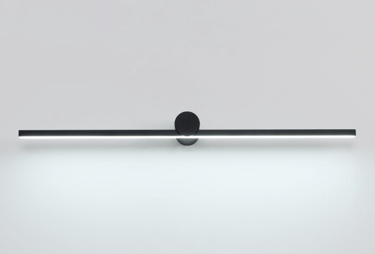 Studio shot of a Clérachic wall light glowing cool white against a plain backdrop, front view.