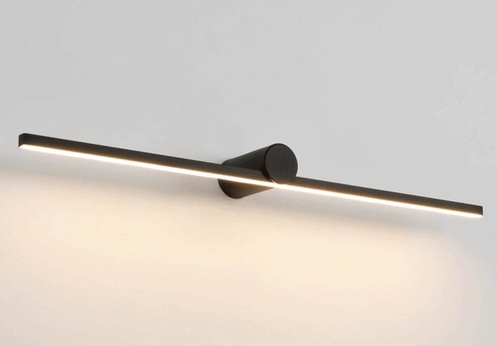 Studio shot of a Clérachic wall light glowing warm at a slight angle against a dark backdrop.