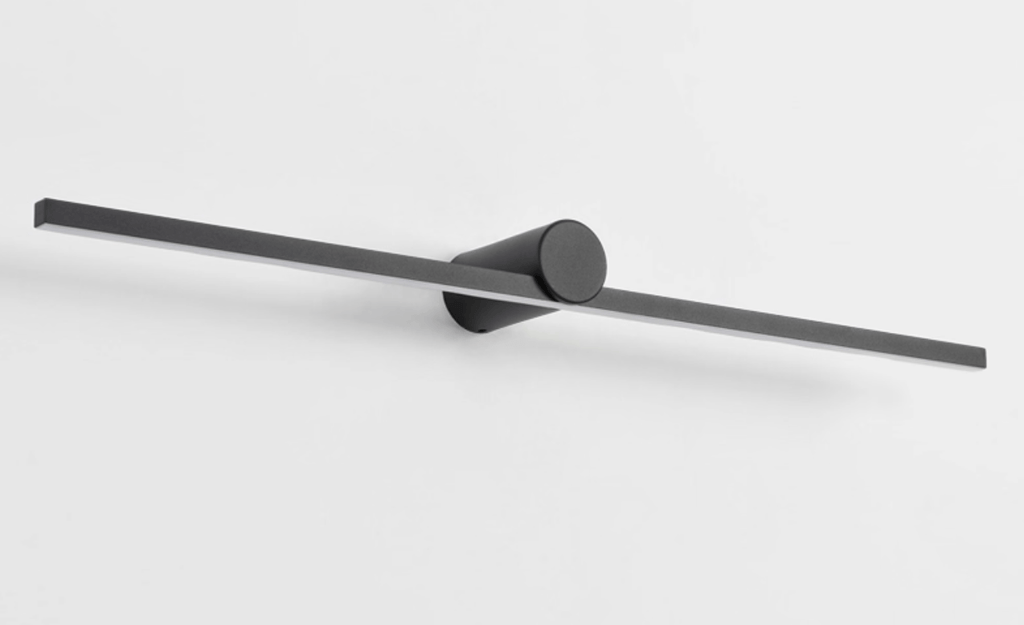Studio shot of an unlit Clérachic wall light, angled to show its slim bar and round pivot mount.