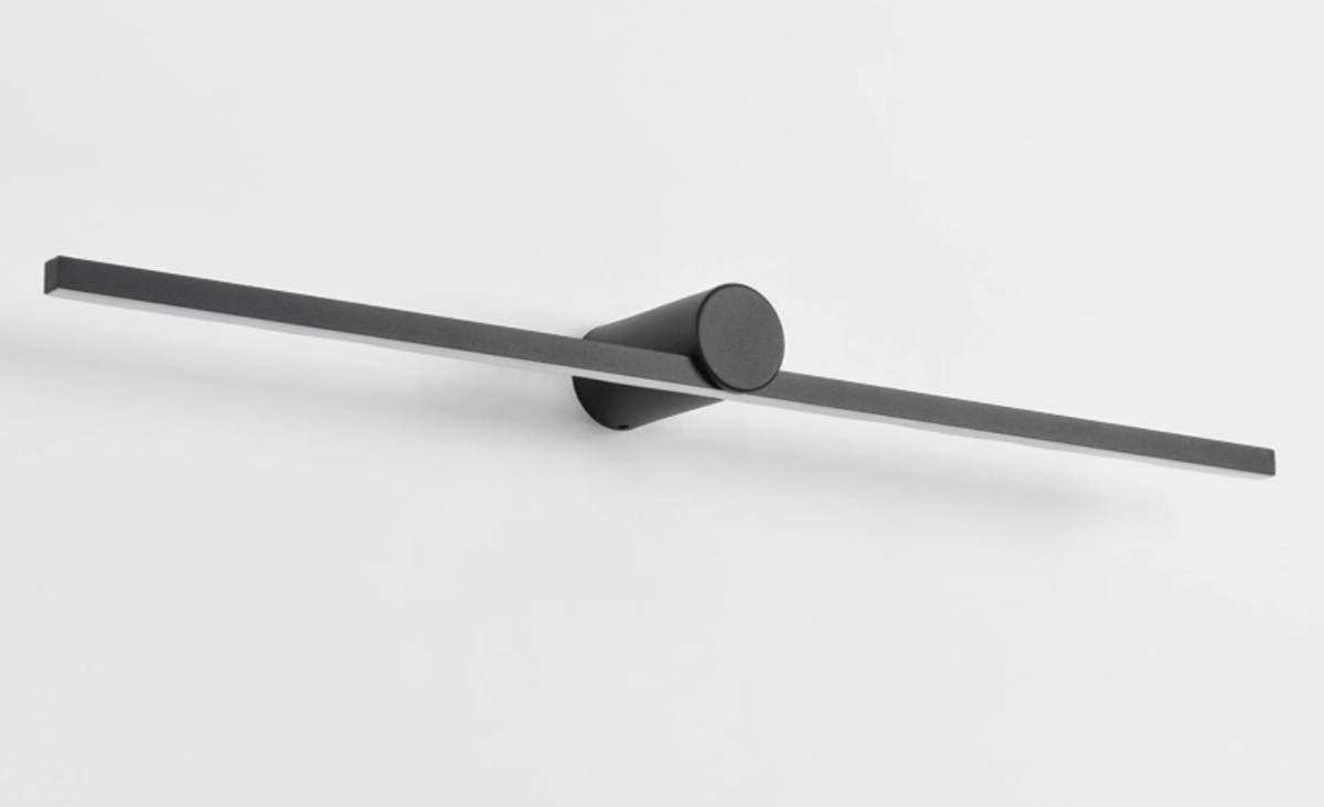 Studio shot of an unlit Clérachic wall light, angled to show its slim bar and round pivot mount.