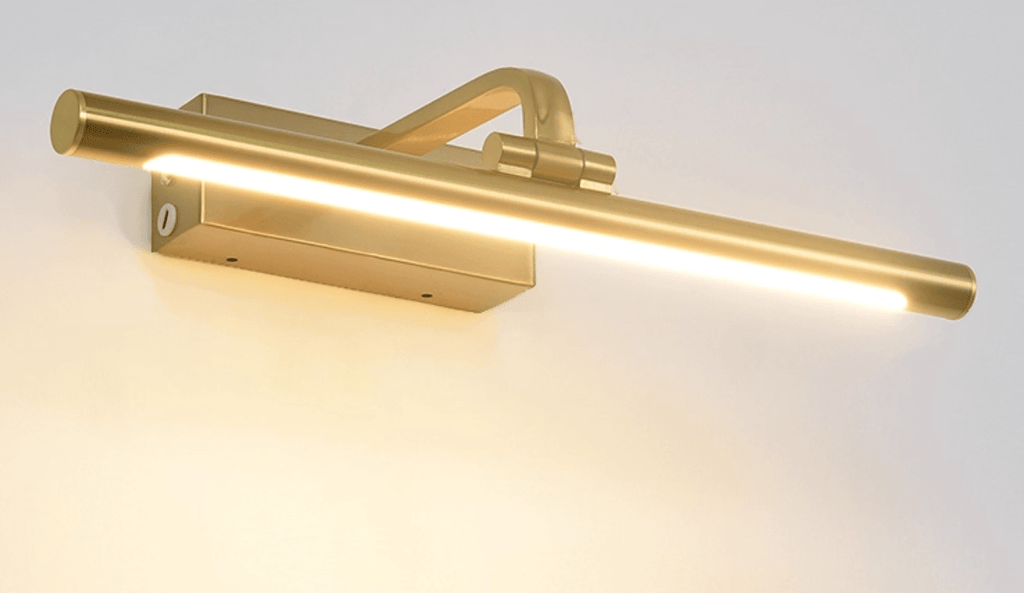 Gold LED wall light with warm glow over decorative artwork