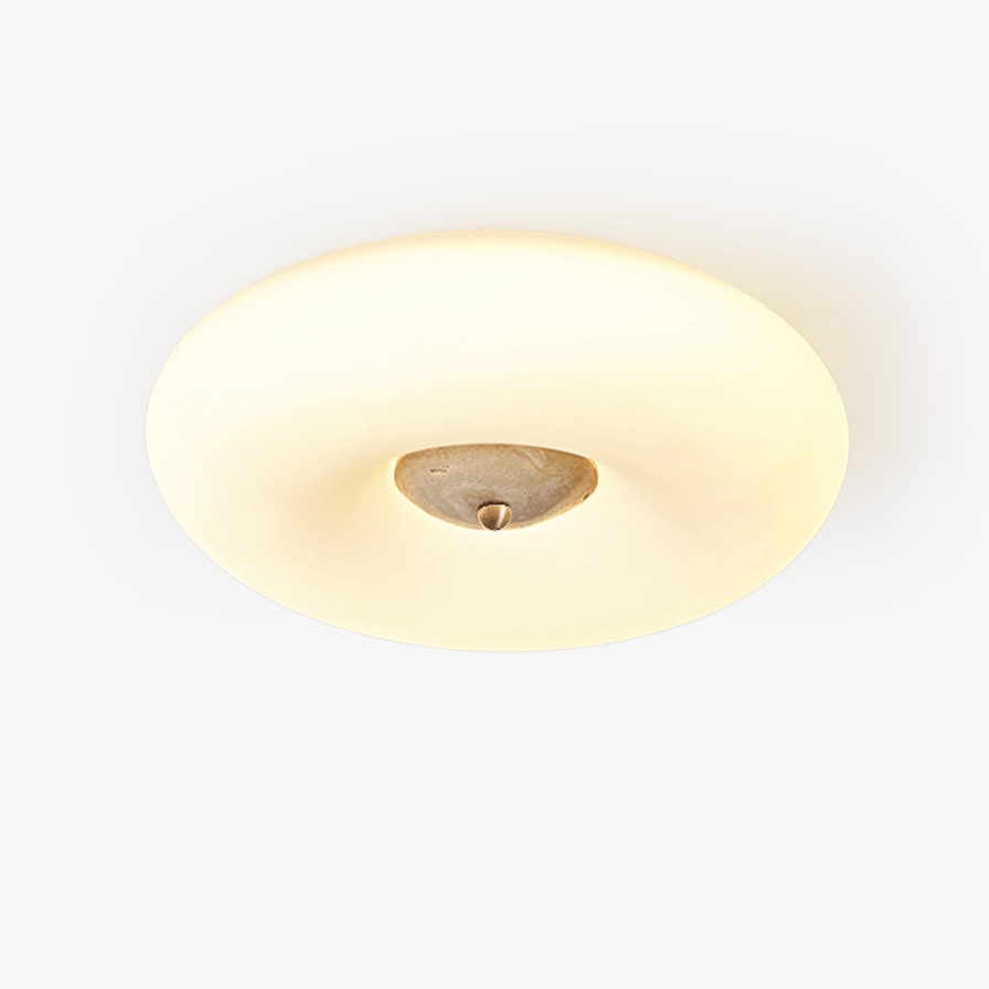 Clérachic ceiling light photographed on a plain background, its warm ring glowing softly around a small pale stone centre.