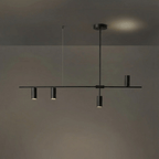 In a dark, low-sheen finish, this Clérachic chandelier hangs against a dim grey backdrop with a warm glow behind.