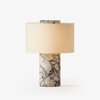 A cream drum shade sits on a white and grey veined marble cylinder, the Clérachic table lamp shown unlit on white.