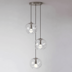 Three small round clear glass shades cascade from a chrome ceiling plate, this Clérachic fixture set against a soft grey backdrop.