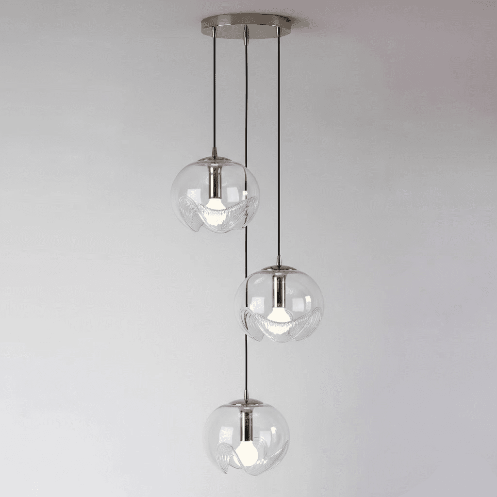Three small round clear glass shades cascade from a chrome ceiling plate, this Clérachic fixture set against a soft grey backdrop.