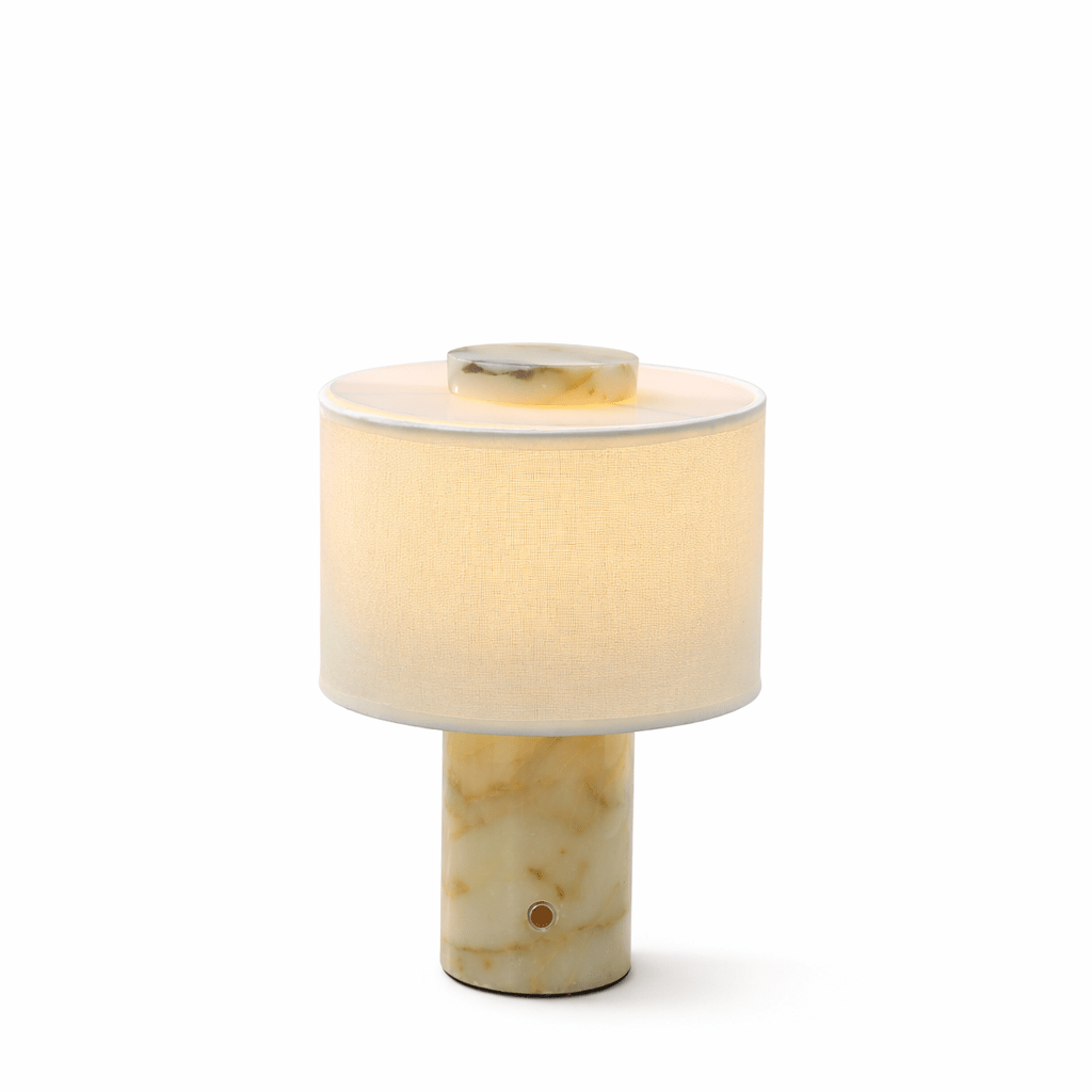 Another angle on the Clérachic table lamp's beige travertine base, isolated against a plain background, lit warm.
