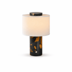 Isolated shot of the Clérachic cordless table lamp's black-and-gold marble base beneath its cream fabric shade.