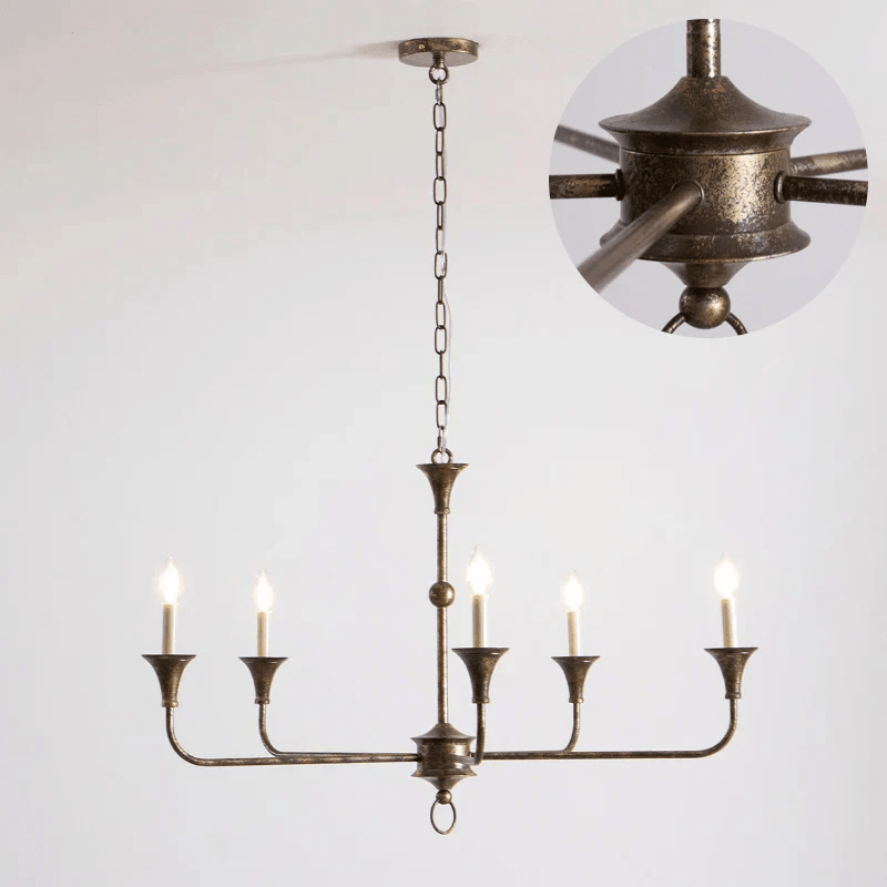 Brass candle chandelier suspended over a dining setting