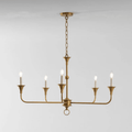 Candle chandelier with slender brass arms and exposed candle-style bulbs, lit in a styled room