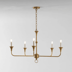 Candle chandelier with slender brass arms and exposed candle-style bulbs, lit in a styled room