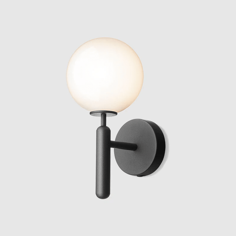This black Clérachic wall light stands unlit against a plain light grey background, its round white glass globe clearly shown.