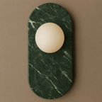 Deep green marble with fine white veining defines this Clérachic wall sconce, photographed close against a taupe backdrop.