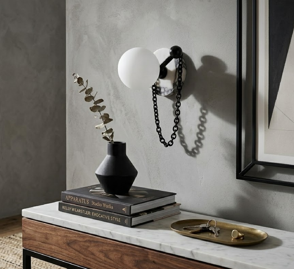 A single Clérachic sconce lights a console styled with dried eucalyptus, stacked books and a brass tray of keys.