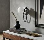 A single Clérachic sconce lights a console styled with dried eucalyptus, stacked books and a brass tray of keys.