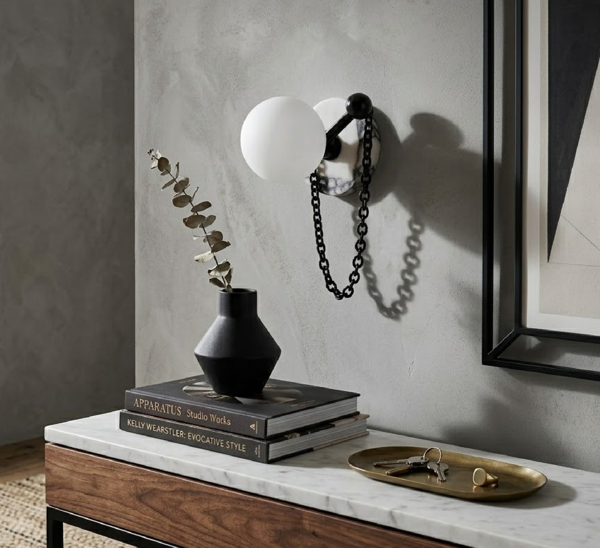 A single Clérachic sconce lights a console styled with dried eucalyptus, stacked books and a brass tray of keys.